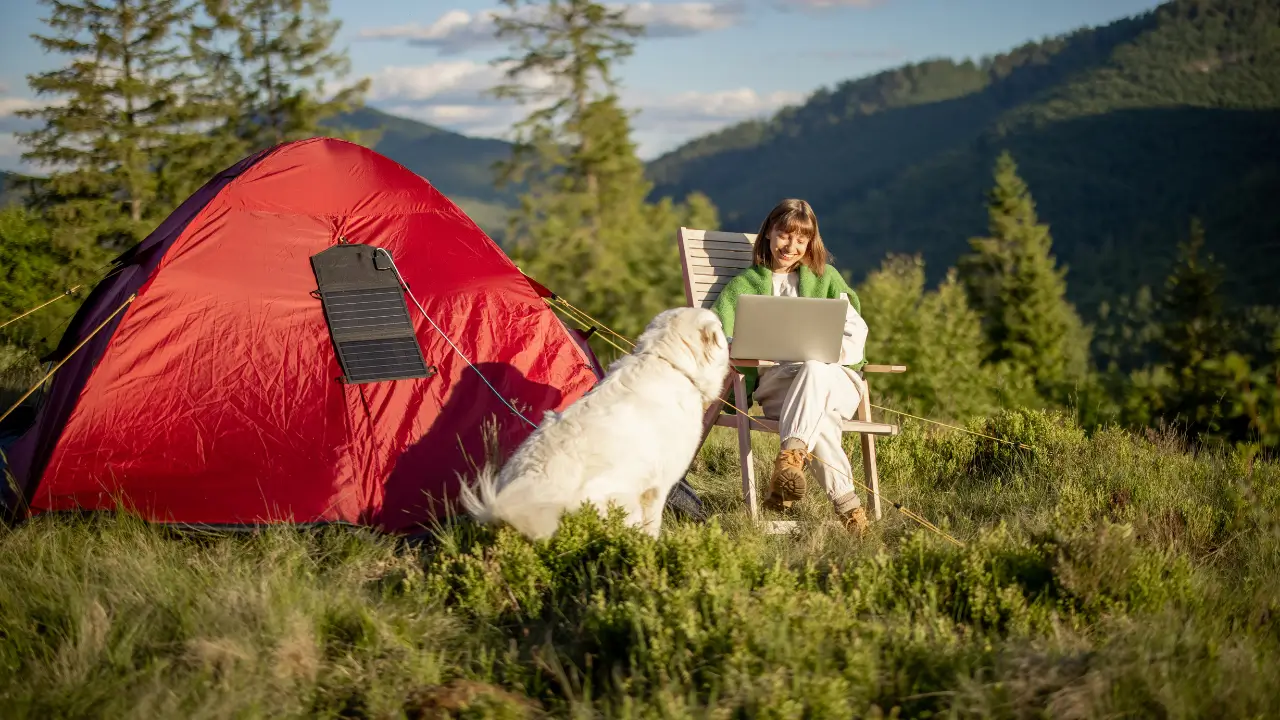Carregador solar portátil em uso durante camping, promovendo tecnologia verde.