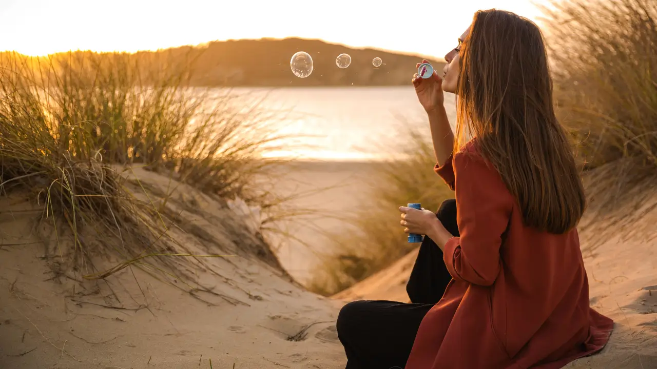 Uma na beira da praia, sem celular, em um cenário natural com tons verdes e terrosos.