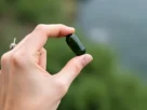 Mão a segurar uma cápsula de água comestível feita de algas, com um fundo desfocado de natureza, simbolizando a inovação das embalagens comestíveis.