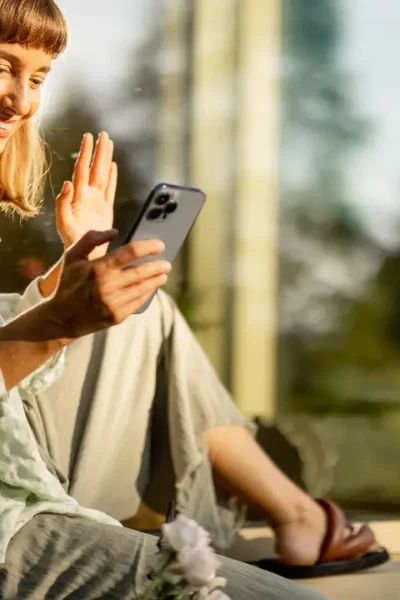 Mulher sorrindo enquanto usa o celular em um ambiente tranquilo, simbolizando o bem-estar diário com o celular.