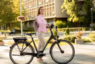 Uma pessoa sorridente numa bicicleta elétrica, numa cidade sustentável ao fundo.