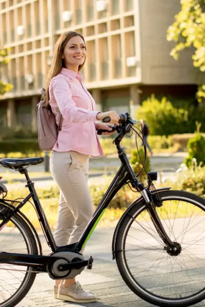 Uma pessoa sorridente numa bicicleta elétrica, numa cidade sustentável ao fundo.