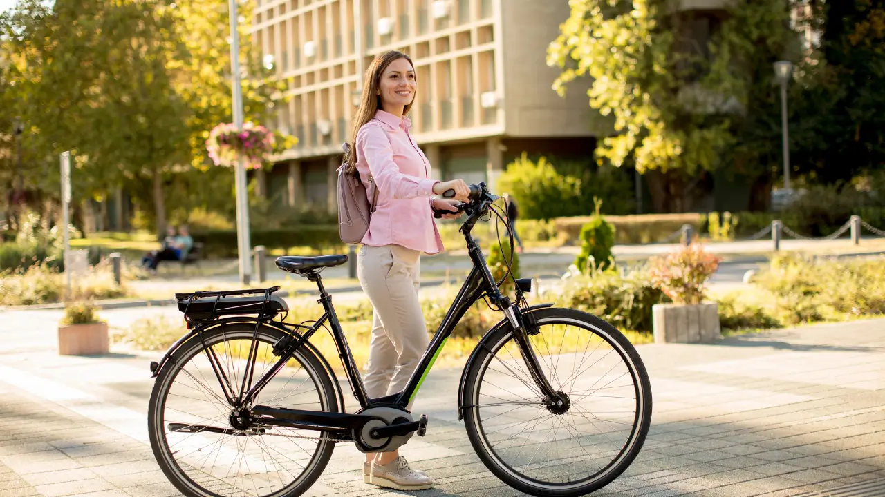 Uma pessoa sorridente numa bicicleta elétrica, numa cidade sustentável ao fundo.