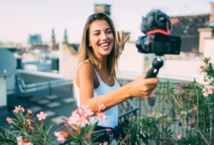 Uma microinfluenciadora de jardinagem a sorrir para a câmera enquanto grava um vídeo sobre plantas.