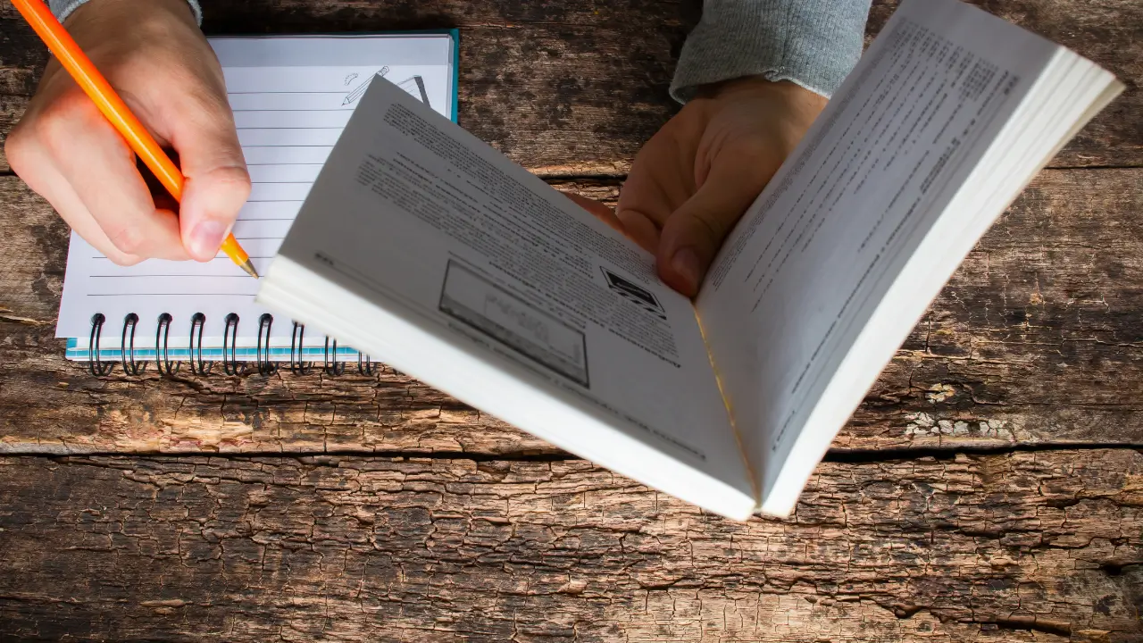 Close-up de uma pessoa a ler atentamente o livro "Profissão influencer" de Fátima Pissarra, com um caderno de notas ao lado.